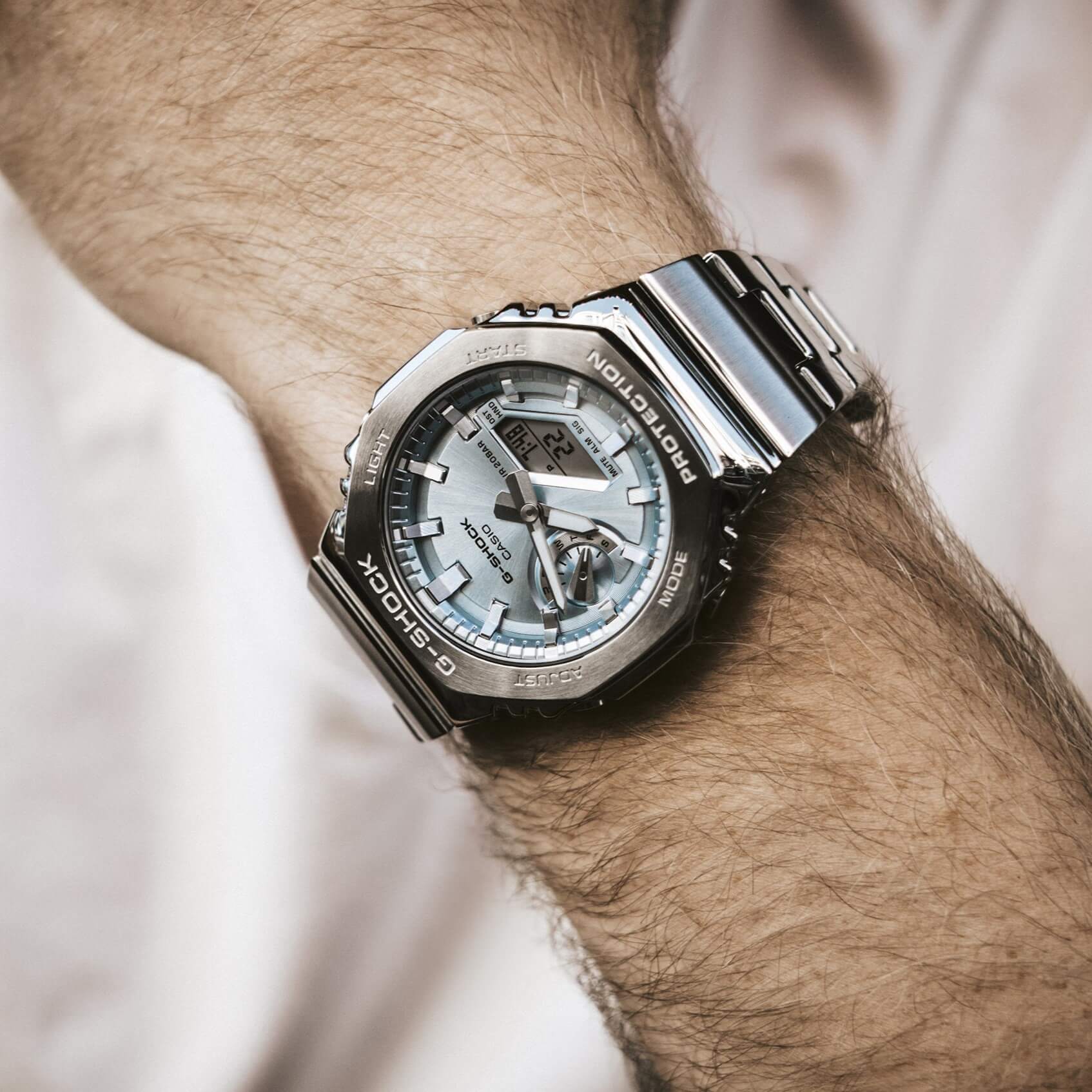 Een man draagt de G-Shock GM-2110D-2AER met een lichtblauwe wijzerplaat en een volledig metalen band.