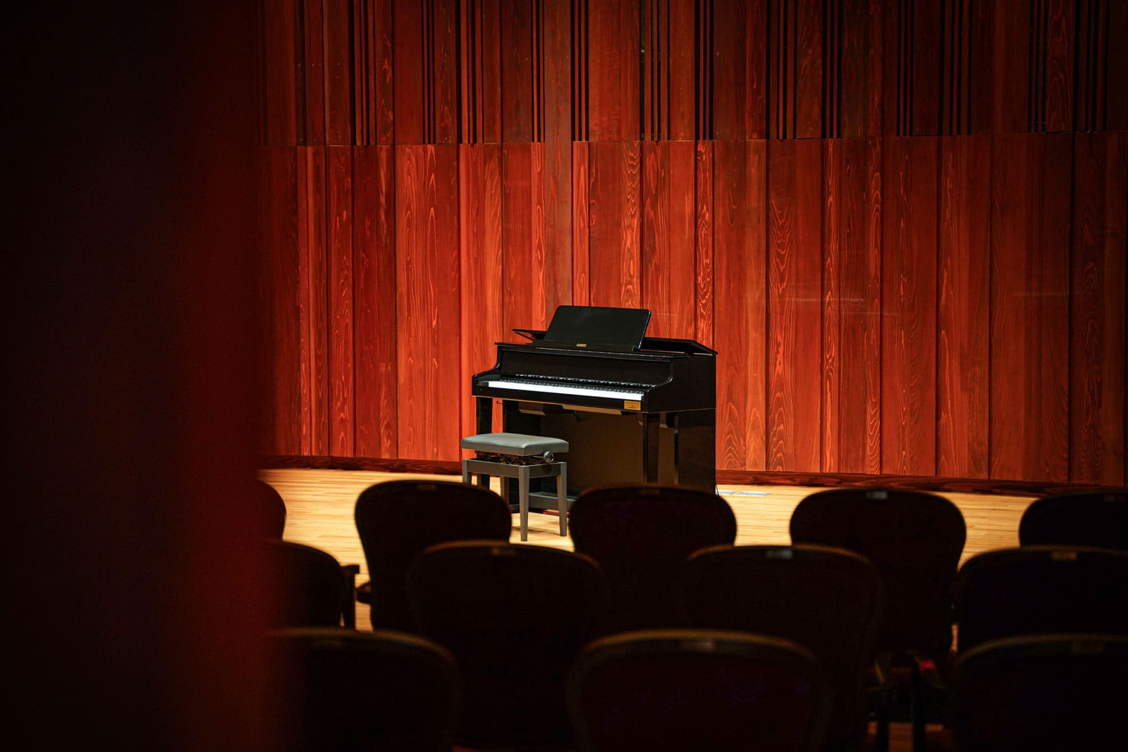 Een zwarte Celviano-piano verlicht op een podium