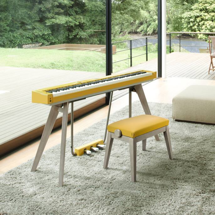 De mosterdgele PX-S7000 staat met bijpassende kruk op een tapijt.