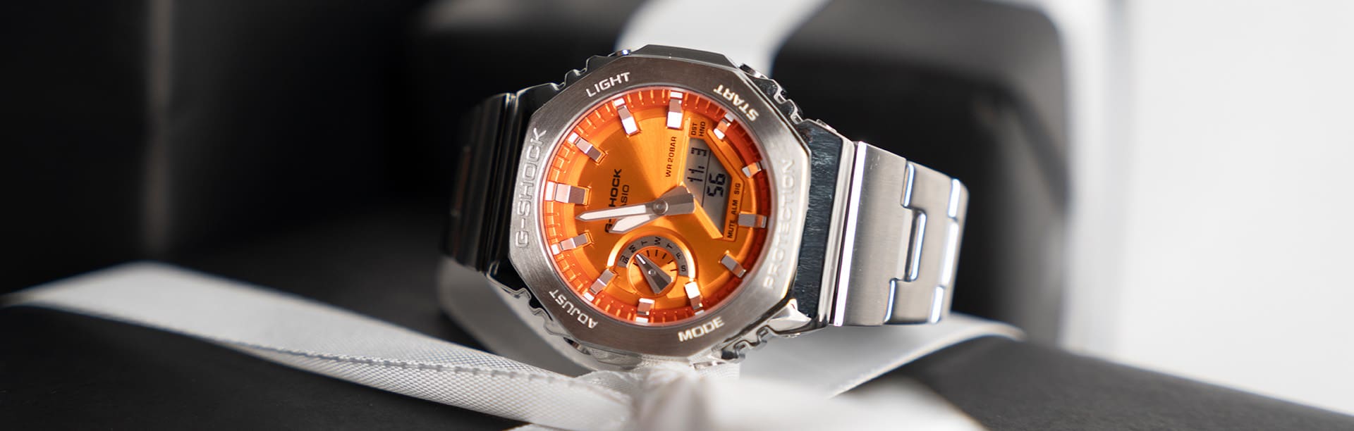 Het analoge G-SHOCK-horloge GM-2110D-4A met oranje wijzerplaat op een stapel kerstcadeaus