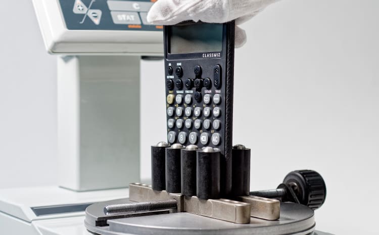 Een CASIO grafische rekenmachine geklemd in een draaiend apparaat.