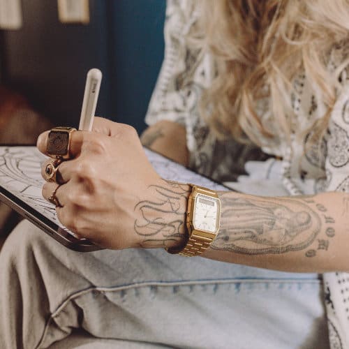 Casio vintage horloge uit de AQ-serie in goud op de arm van een getatoeëerde vrouw
