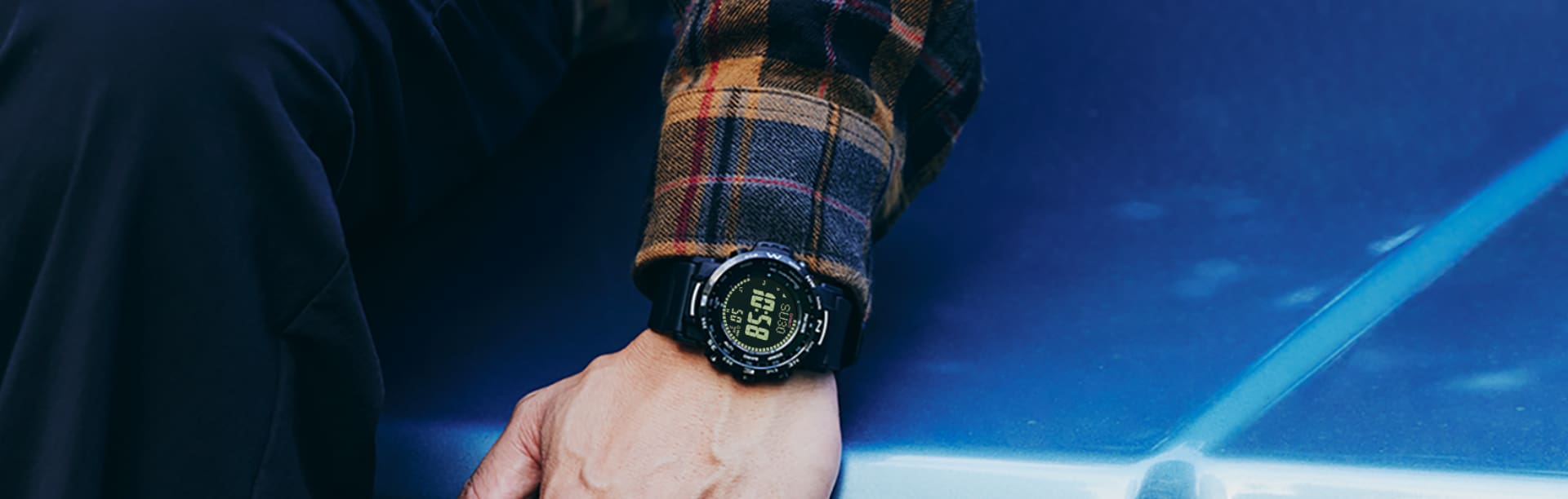 PRW-35Y-1B Pro Trek polshorloge met digitaal display om de pols van een persoon die op een motorkap leunt