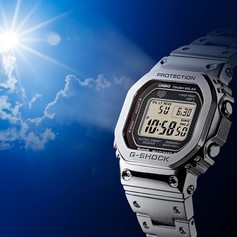 Een G-SHOCK horloge met een zilverkleurig bandje wordt tegen het zonlicht gehouden.