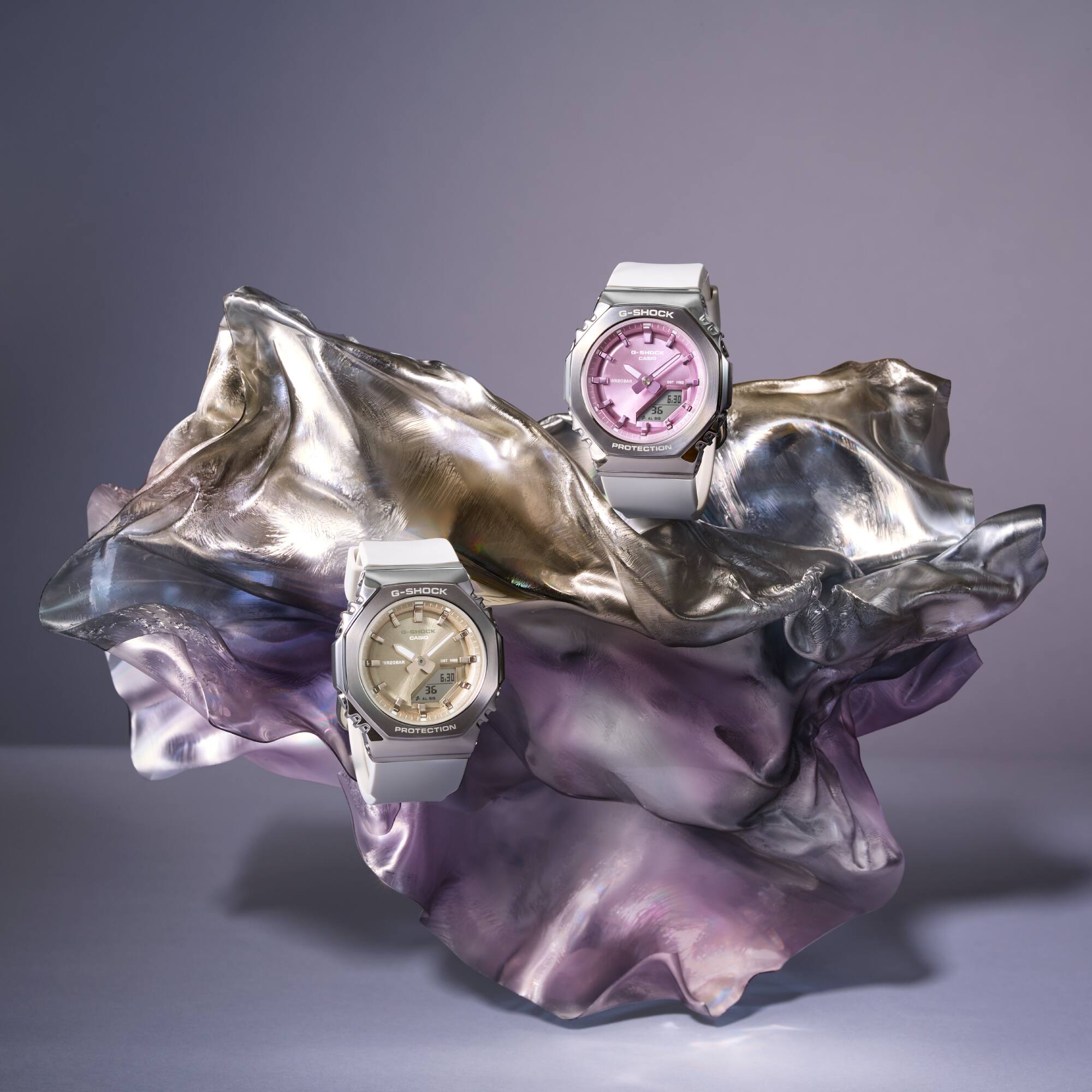 De G-Shock Classic hybride polshorloges GM-S2110-7A9 en GM-S2110-7A6 met witte band en gekleurde wijzerplaten. De afbeelding linkt naar de GM-S2110-7A6 met een roze metallic wijzerplaat.