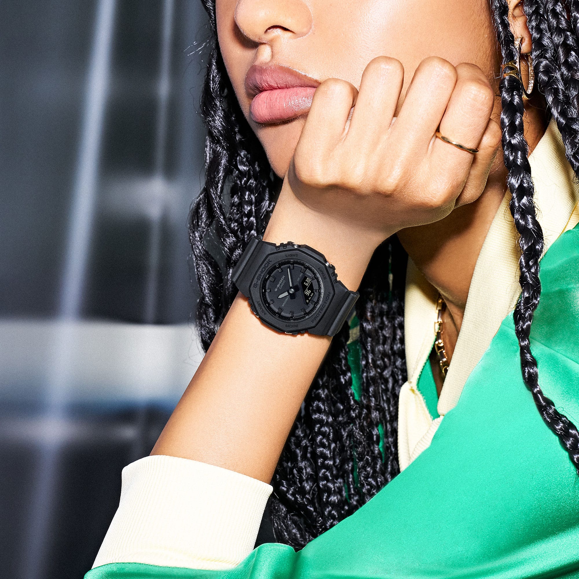 Het GMA-P2100BB-1A hybride polshorloge van CASIO G-SHOCK om de pols van een sportief geklede vrouw die met haar hoofd op haar hand leunt