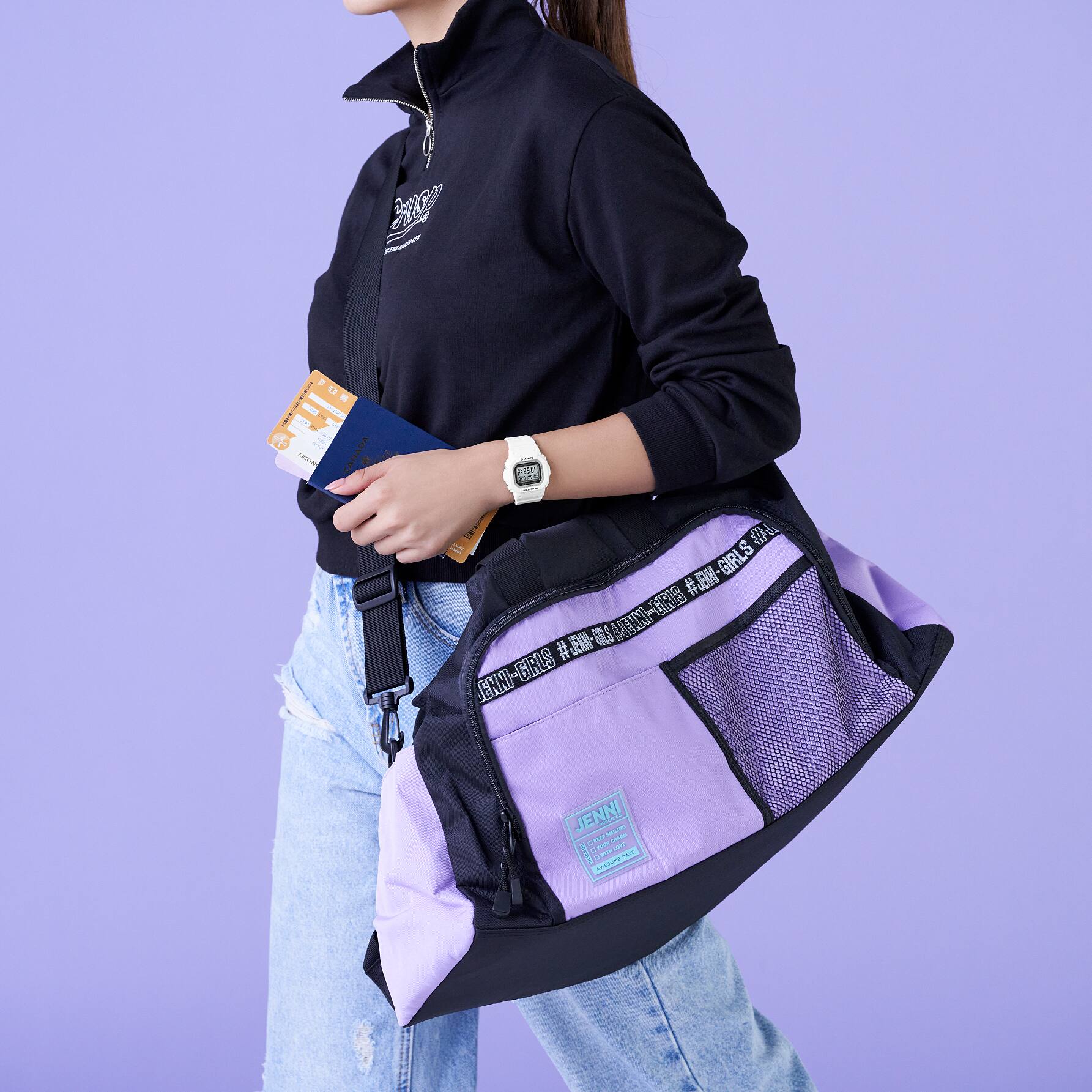 Het witte CASIO BABY-G BGD-5650-7 polshorloge op de arm van een casual geklede vrouw met een sporttas