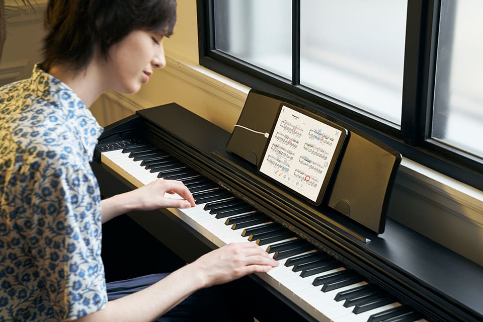 Um homem mostra a partitura enquanto toca piano.