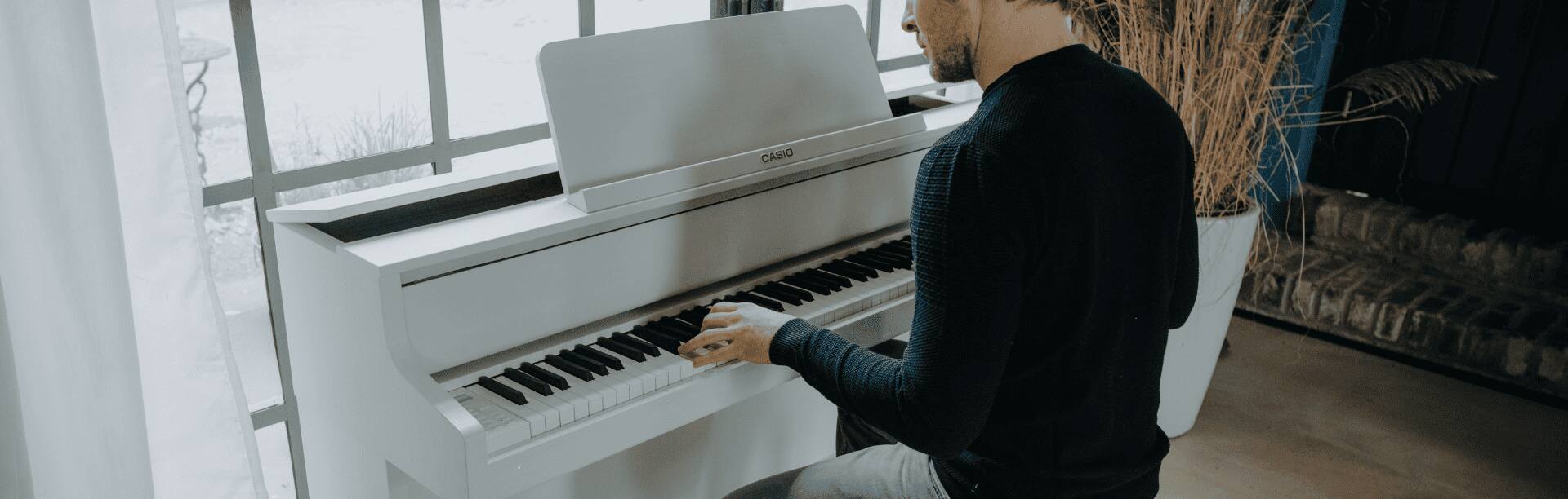 Um homem toca no piano branco GP-310WE da série Grand Hybrid.