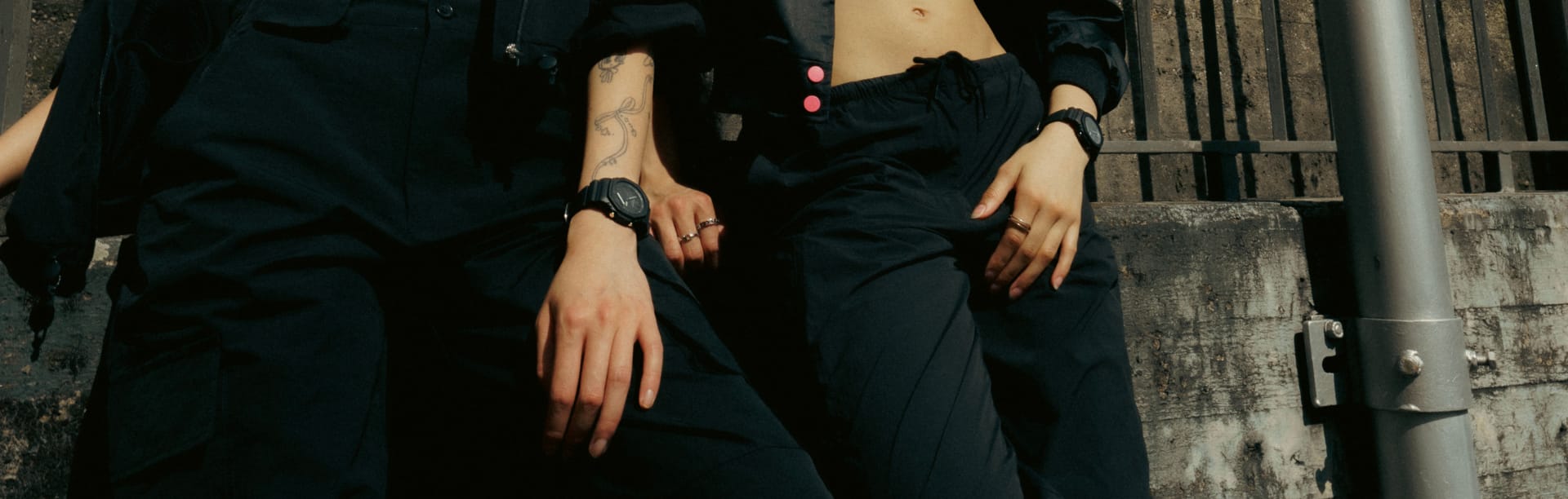 Duas mulheres vestidas de preto usam os relógios de pulso pretos GA-2100-1A1 e GMA-P2100BB-1A