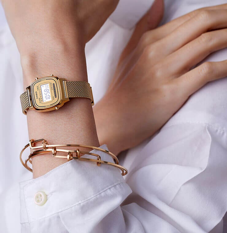 O relógio CASIO VINTAGE La670 com uma bracelete dourada no pulso de uma mulher