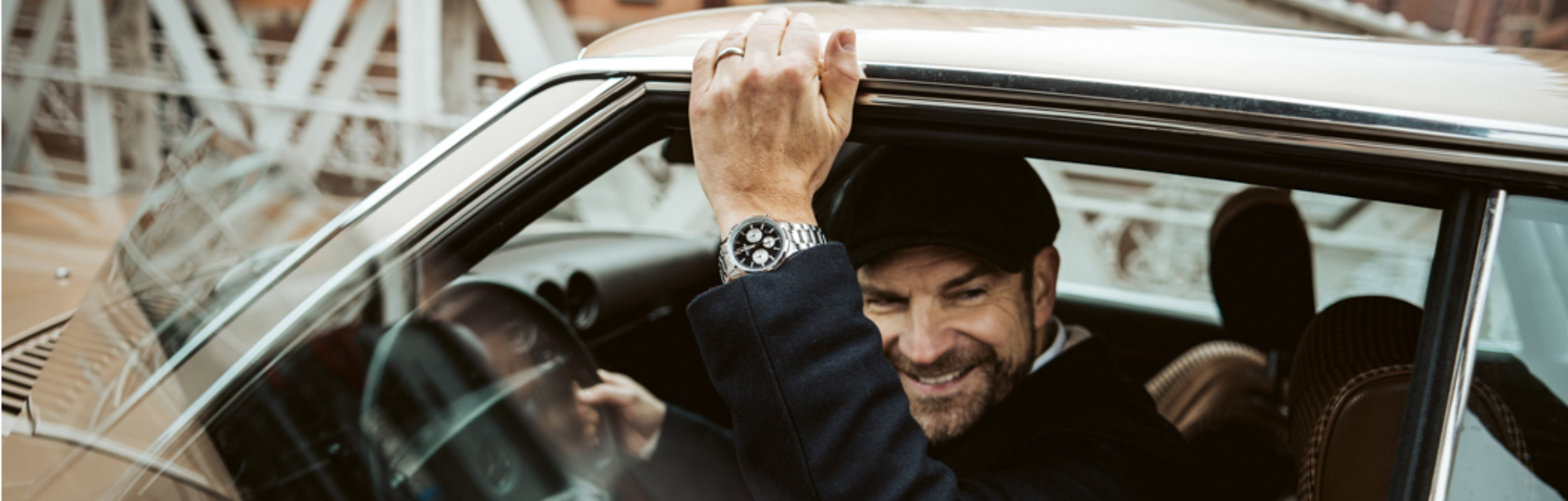 Um homem usa o EFR-575D-1AEF da EDIFICE e senta-se num carro histórico numa ponte em Hamburgo.