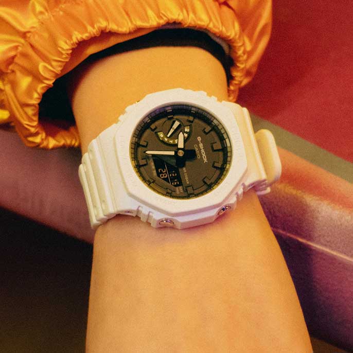 O G-Shock GA-2100-7A com pulseira de resina branca e mostrador preto. A imagem tem um link para a página do produto.