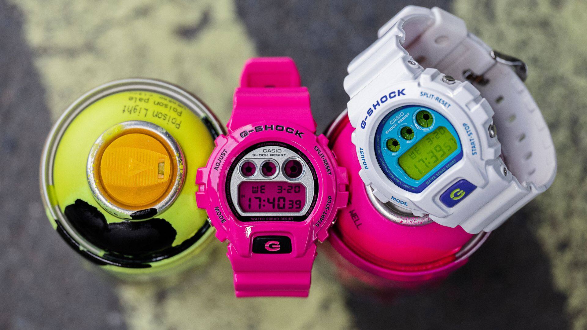 Os relógios de pulso G-Shock Crazy Colour brancos e cor-de-rosa em latas de graffiti com cores combinadas.