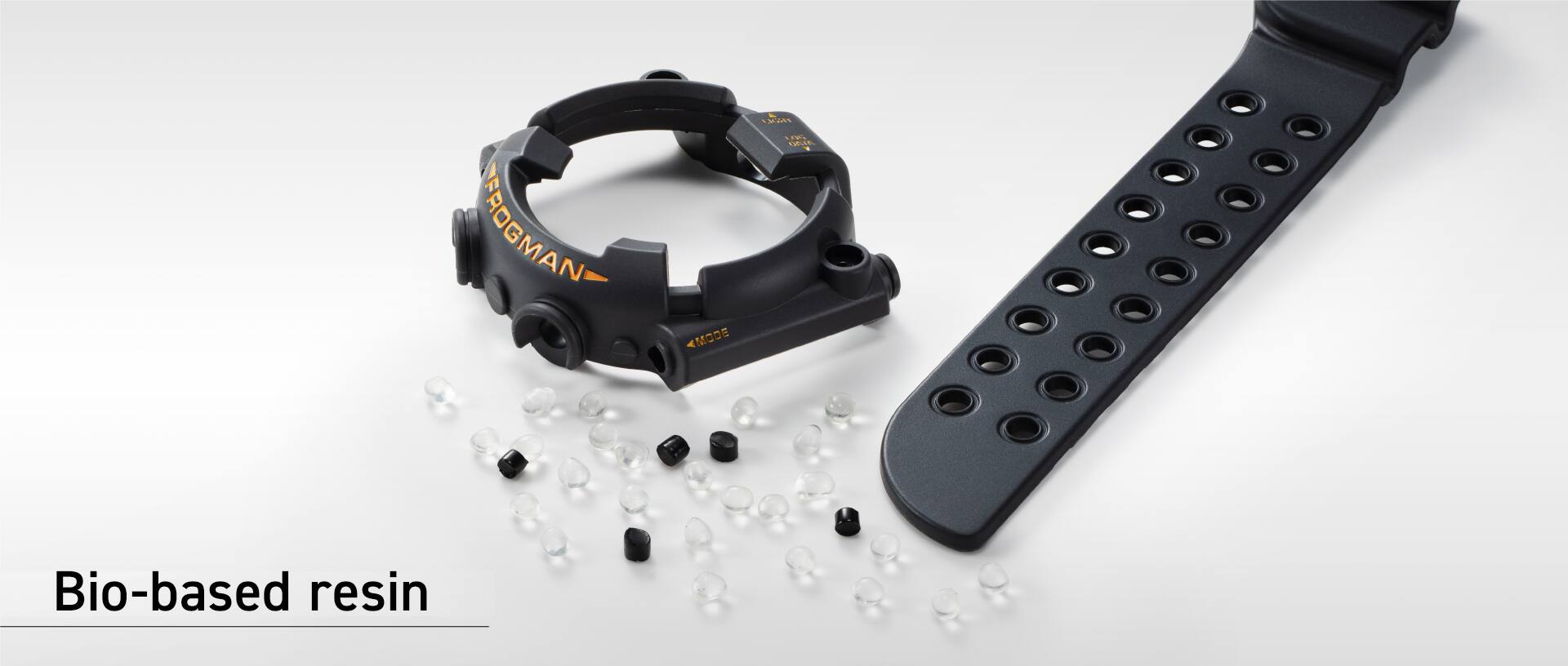 A caixa e a bracelete pretas de um relógio G-SHOCK estão ao lado de pellets feitos de resina de base biológica.