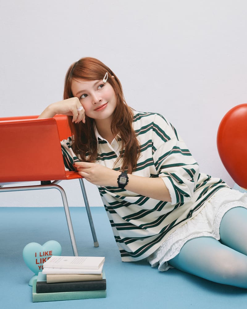 BGD-10KH-1 on the wrist of a girl wearing white clothing is leaning against a chair.