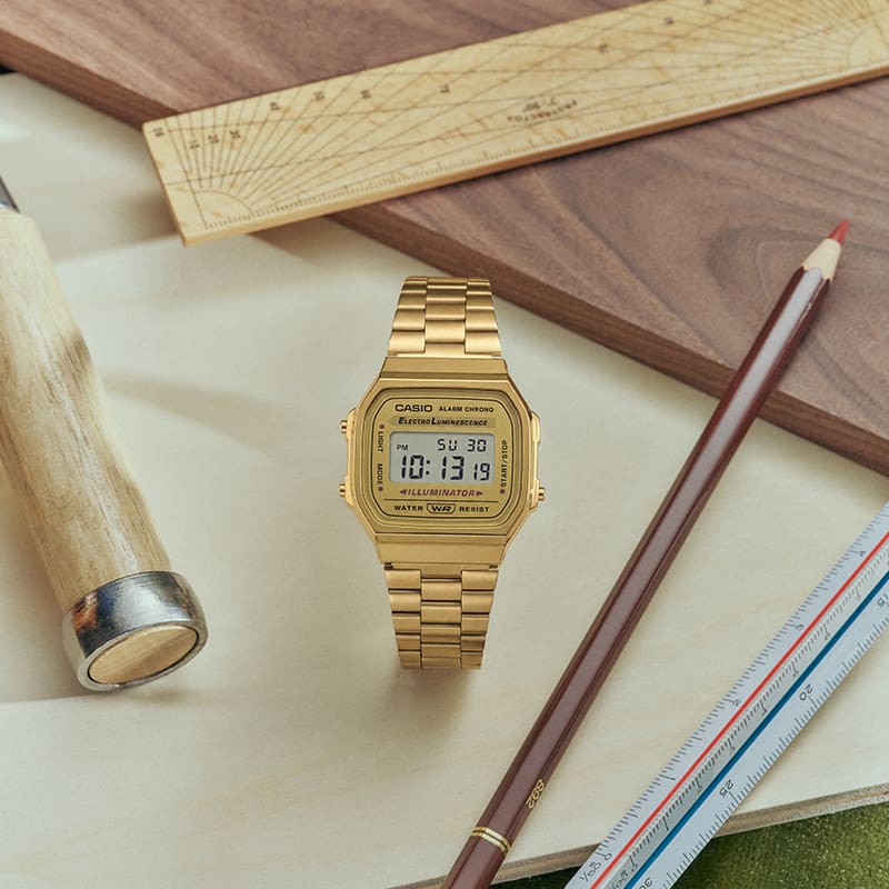 照片呈現與工具和文具擺放在一起的 G-SHOCK A168WG-9。