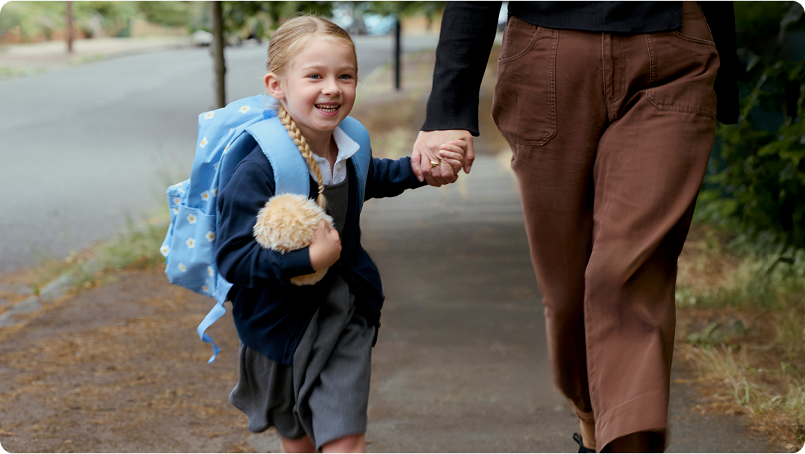 An image of a girl carrying a gold-colored Moflin in her right hand, holding her mother's hand with her left, smiling as they walk together.