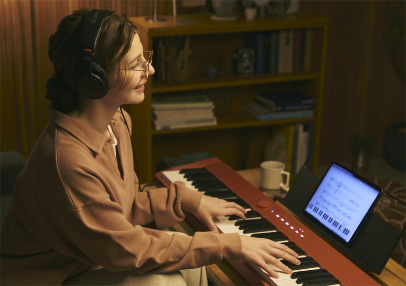 Image of a person with a headphone playing the keyboard with the app displayed on the tablet