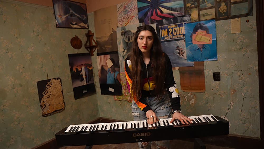 Veronica Lewis playing Casio Keyboard in a room with posters
