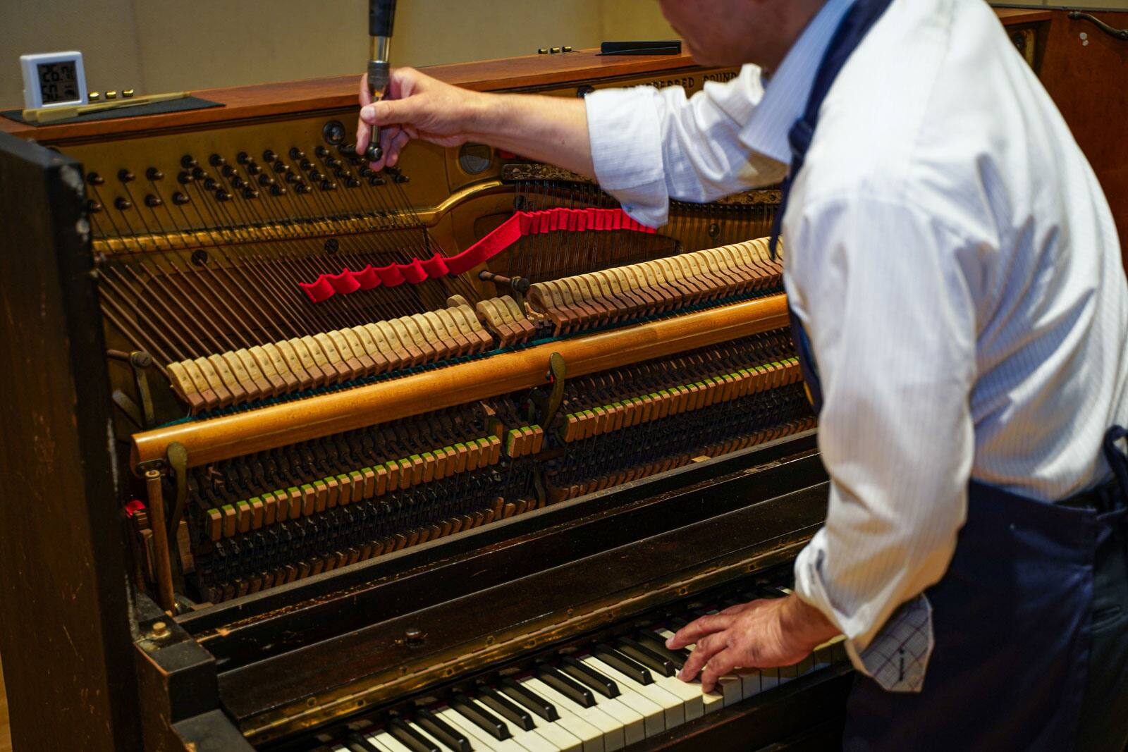 A photo of a man tuning Akiko's piano