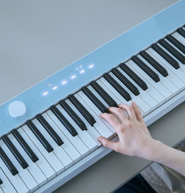 An image of a person playing the Clam Blue colored piano