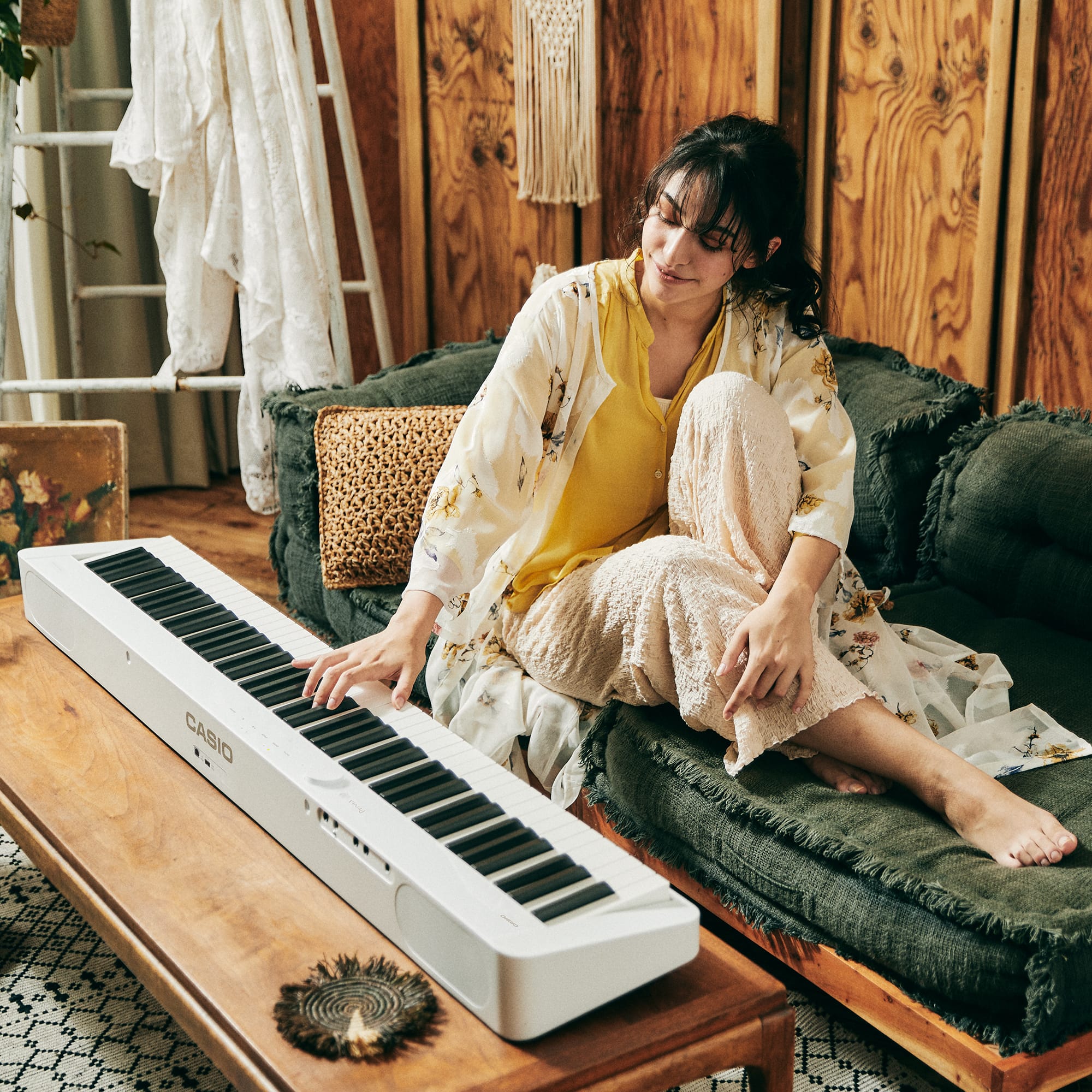 A woman casually playing a Casio Privia PX-S1100WE 88-key digital piano denoting style.
