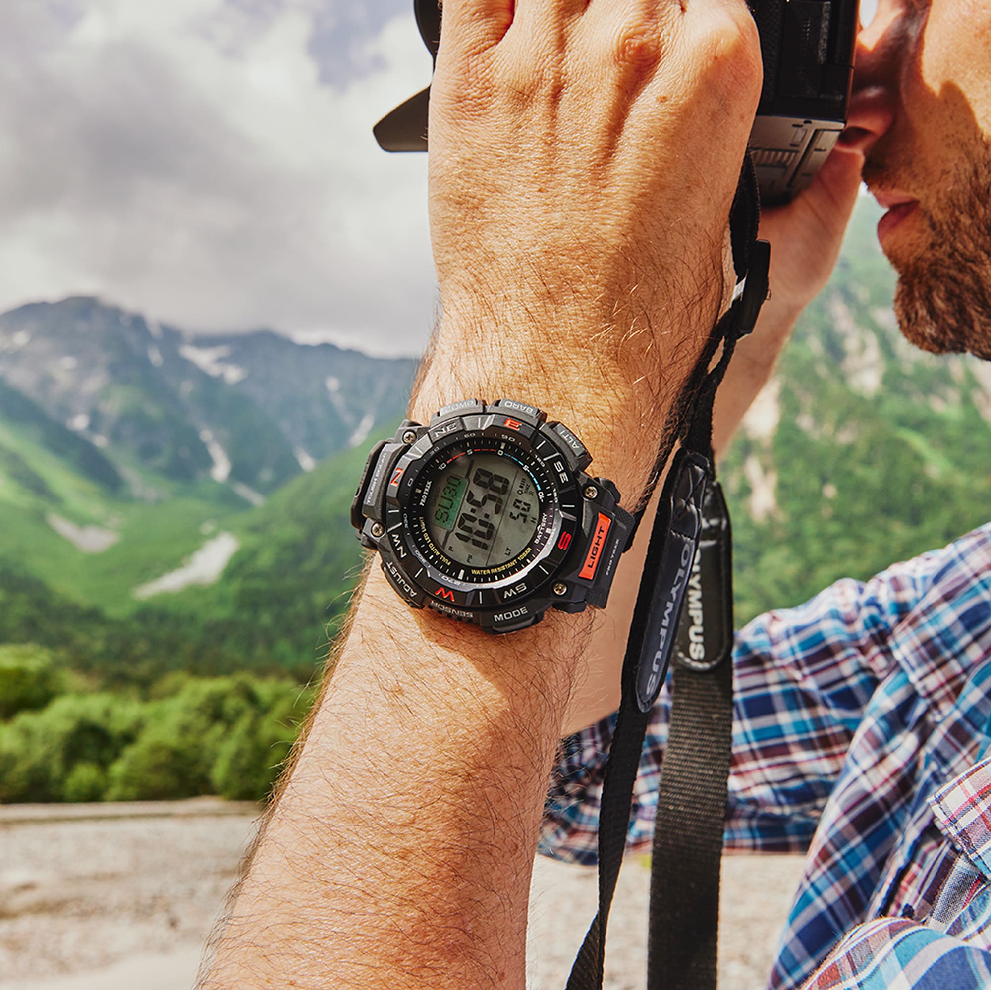 Casio Pro Trek PRG340-1 on a hiker’s wrist displaying the time and denoting the precision in an outdoor landscape