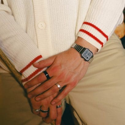Ein Mann trägt die A130WE-7AEF am Handgelenk und hat eine weiße Strickjacke und eine beige Hose an