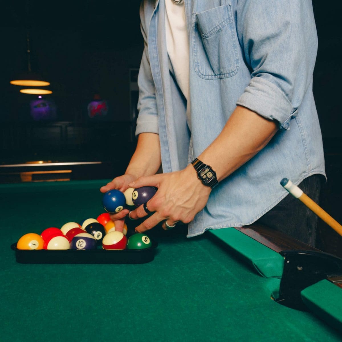 Ein Mann trägt die A130WEGG-1AEF am Handgelenk und hat ein blaues Jeanshemd mit weißem T-Shirt an