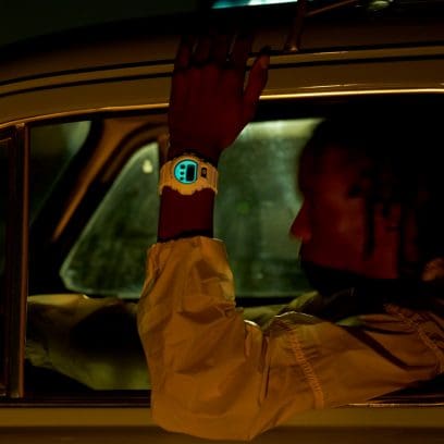 DW-6900HDS-7ER am Handgelenk einer dunkelhäutigen Person in einem dunkel beleuchteten Auto. Das leuchtende Zifferblatt ist im Dunkeln zu erkennen