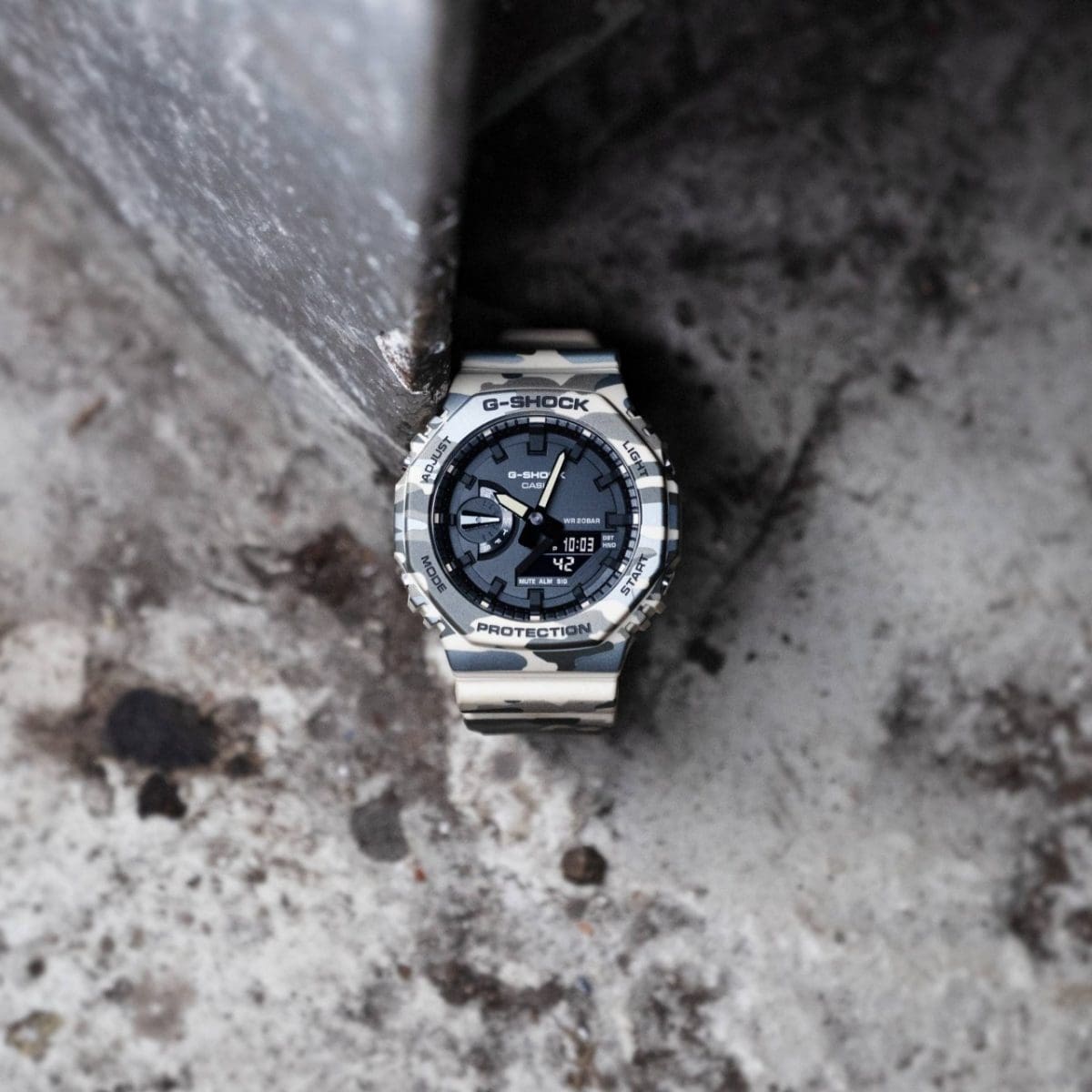 Die Armbanduhr GA-2100CM-5AER von G-SHOCK steht auf einem steinernen Untergrund