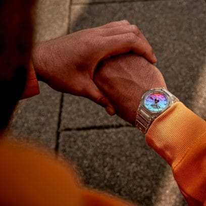 Die GA-2100SRS-7A am Handgelenk eines Mannes mit einem orangenen Pullover