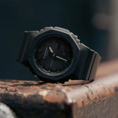 Die komplett schwarze GMA-92100BB-1A Armband Uhr von G-SHOCK liegt auf einem Stahlträger