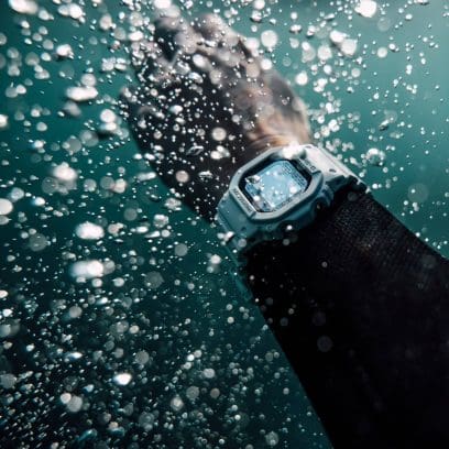 An dem Handgelenk eines Armes unter Wasser ist die weiße GW-5000HS-7ER zu sehen. Im Wasser steigen Luftblasen auf.