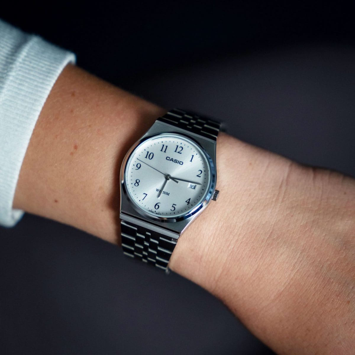 Nahaufnahme der MTP-B145D-7BV Armbanduhr mit silberfarbenem Armband am Handgelenk einer Frau.