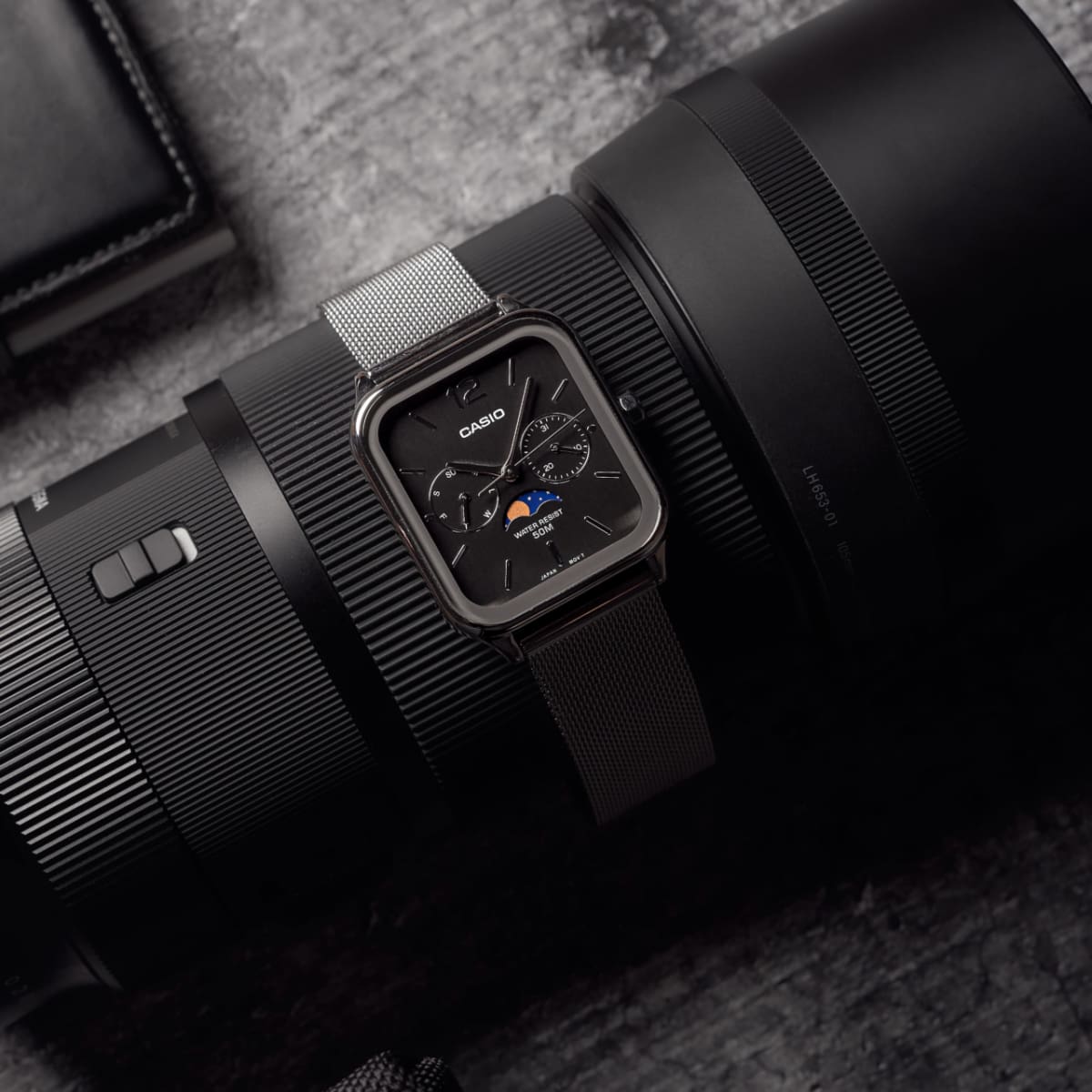 Die CASIO TIMELESS COLLECTION Armbanduhr MTP-M305M-1AV auf einem schwarzen Kameraobjektiv drapiert.