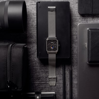 Komplettansicht der flach liegenden CASIO TIMELESS COLLECTION Armbanduhr MTP-M305M-1AV inmitten verschiedener Schreibtisch- und Fotografie-Utensilien.