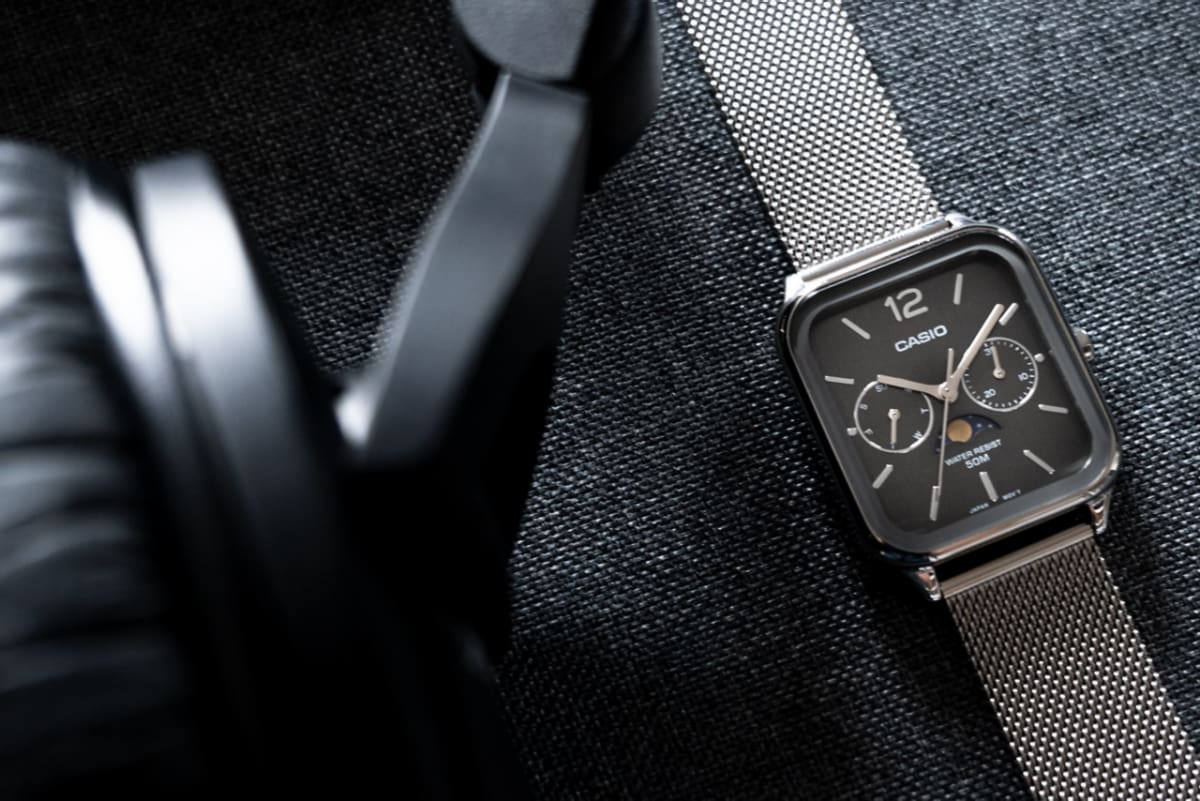 Ansicht der flach liegenden CASIO TIMELESS COLLECTION Armbanduhr MTP-M305M-8AV neben einem Kopfhörer.