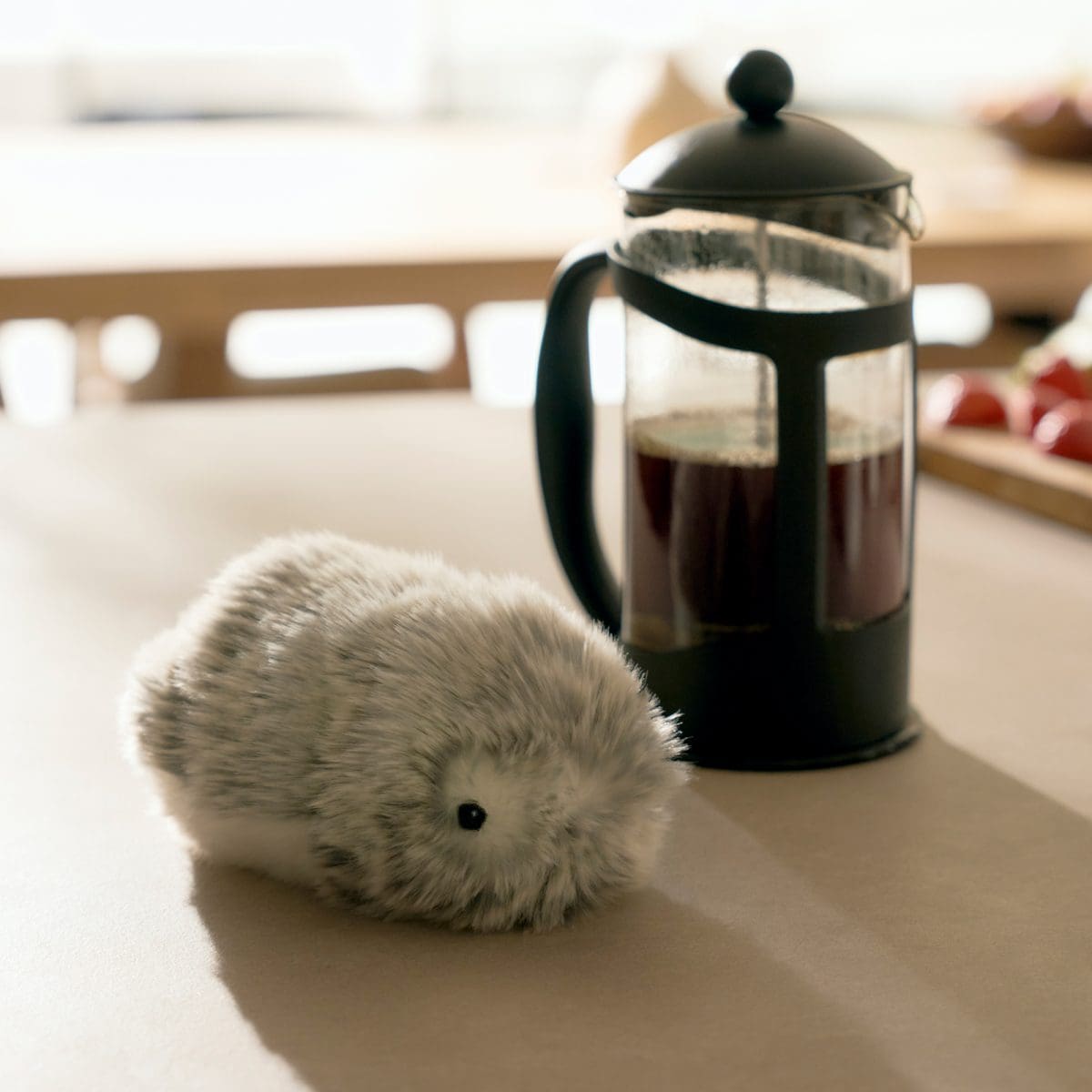 Das Moflin sitzt auf einem Tisch mit einem Kaffeezubereiter daneben