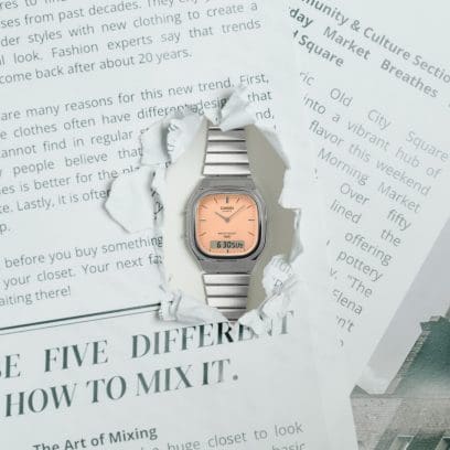 Die analog-digitale Armbanduhr AQ-240E-4AEF schaut durch ein in eine Zeitung gerissenes Loch hindurch