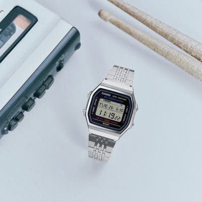 Die Uhr ABL-100WE-1A mit Schlagzeugstöcken und Audiogeräten platziert.