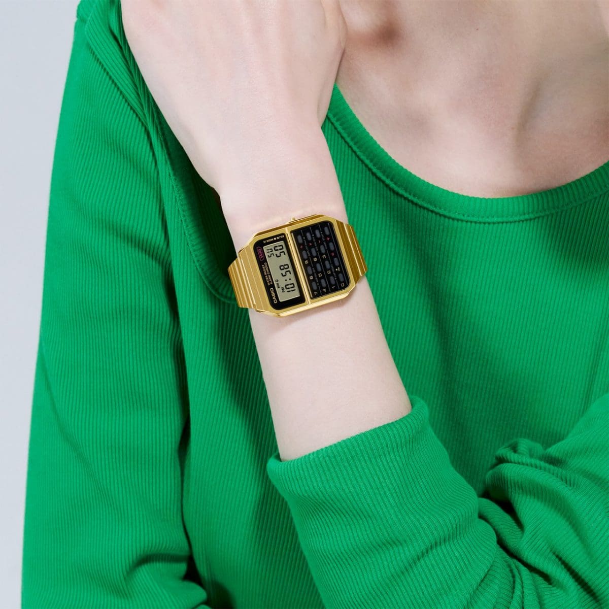Die goldfarbene CASIO Armbanduhr CA-500WEG-1A an einem Damenhandgelenk, die Dame trägt ein grünes Shirt