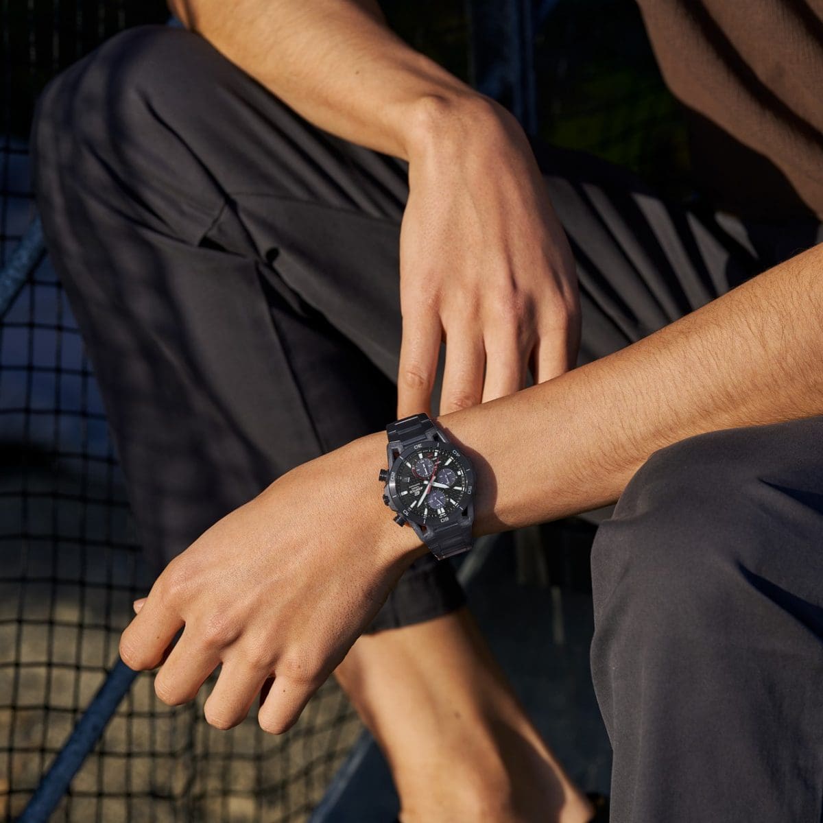 Halbtotale von einem Mann inder Hocke, der die schwarze Armbanduhr EFS-S640DC-1AV von EDIFICE trägt.