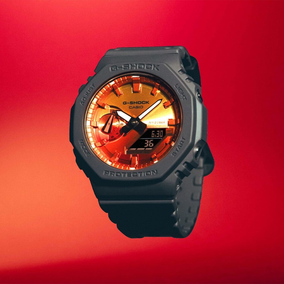 G-SHOCK GA-2100FL-8A mit orangenem Zifferblatt und grauem Armband vor einem roten Hintergrund