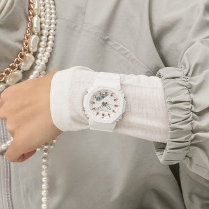 Die weiße GMA-P2100M-7A am Handgelenk einer Frau. Diese trägt einen weißen Pullover und eine graue Jacke