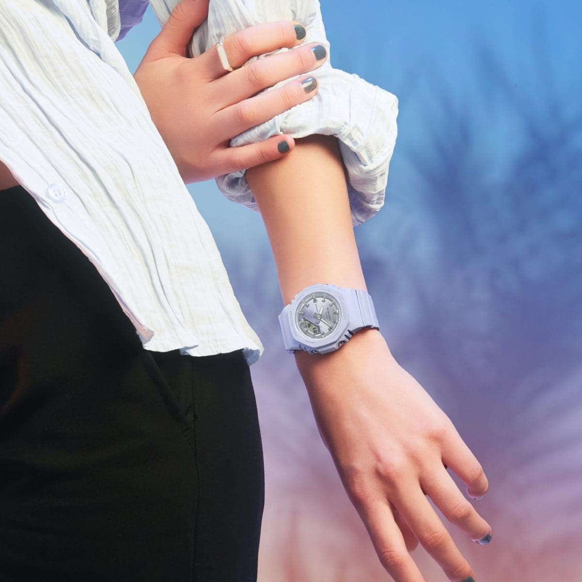 Halbtotale einer Frau, die eine weiße Bluse hochgekrempelt und am Handgelenk die fliederfarbene GMA-P2100SG-2AER Armbanduhr von G-SHOCK trägt