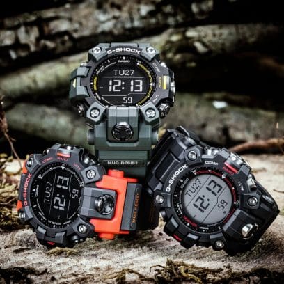 Drei verschiedene G-SHOCK Digitaluhren aus der GW-9500-Reihe auf einem Baumstamm