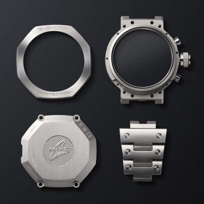 Lünette, Gehäuse, Rückseite und Gliederarmband der MRG-B2100D-2ADR nebeneinander auf schwarzem Untergrund