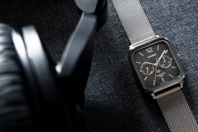 Ansicht der flach liegenden CASIO TIMELESS COLLECTION Armbanduhr MTP-M305M-8AV neben einem Kopfhörer.